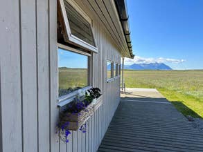 The outside of the Hestaland Horse Farm Cottage, with mountains and fields in the background.