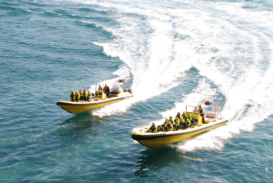 RIB boat tour near Thridrangar Lighthouse with travelers speeding across the Atlantic Ocean in South Iceland