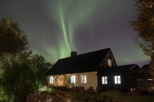 The aurora borealis dancing over a house in south Iceland in winter.