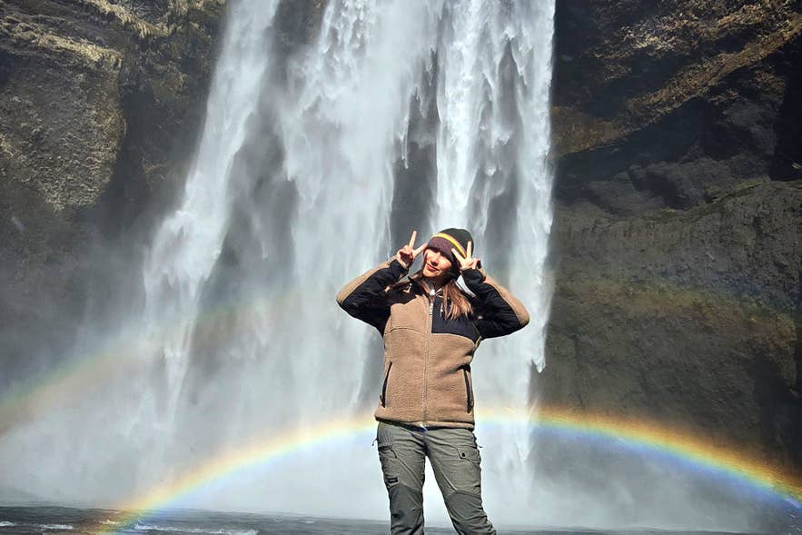 Traveler at Skogafoss waterfall with a rainbow Traveler at Skogafoss waterfall with a rainbow