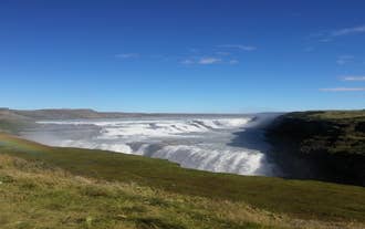 The golden falls of Gullfoss and a rainbow made out of its mist, on a summer day in Iceland at the Golden Circle sightseeing route.
