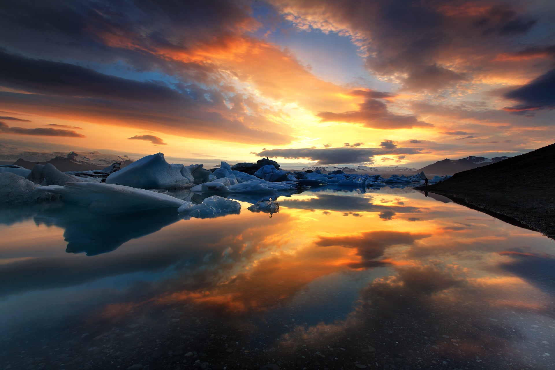 Il cielo colorato si riflette perfettamente sulla superficie immobile del lago più profondo d'Islanda, la laguna del ghiacciaio Jokulsarlon