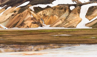 A close-up view of a mountain base on the Laugavegur trail in the Icelandic Highlands shows the different shades of color and patches of snow that adorn the mountains here.