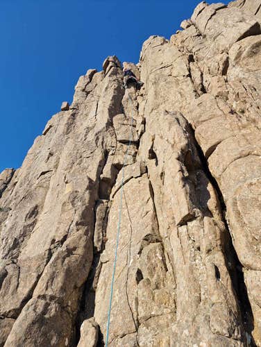 A person near the top of a rock face during summer in Iceland.
