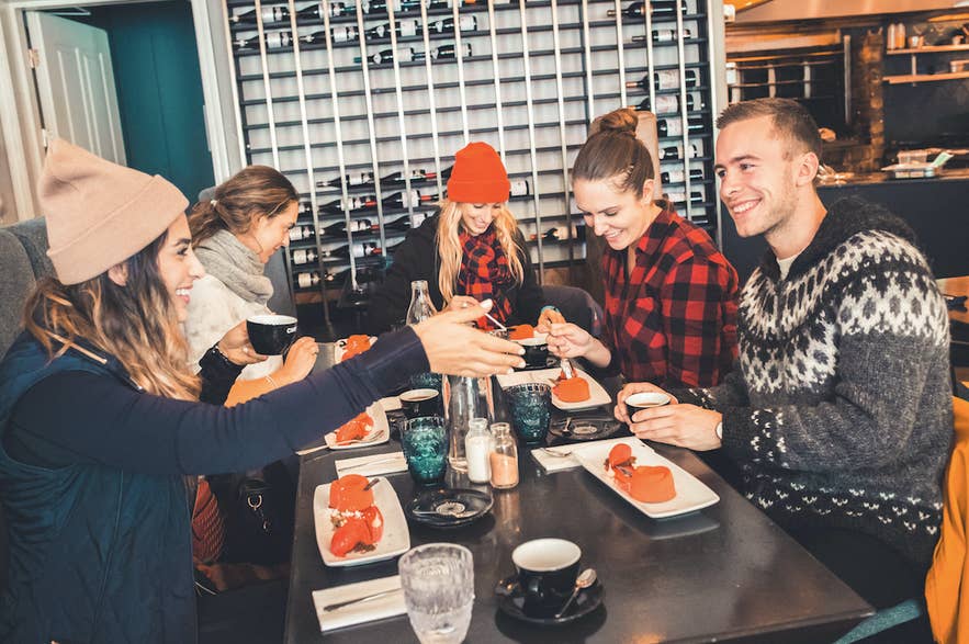 Travelers toasting over small plates on Wake Up Reykjavik's food walk, the best-rated food tour in Iceland.