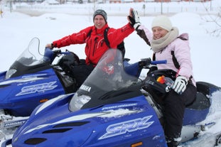 Zwei Personen geben sich ein High Five auf einer Schneemobiltour in Nordisland.