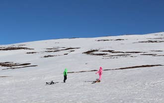 Two people walk with sleds on a tour in North Iceland.