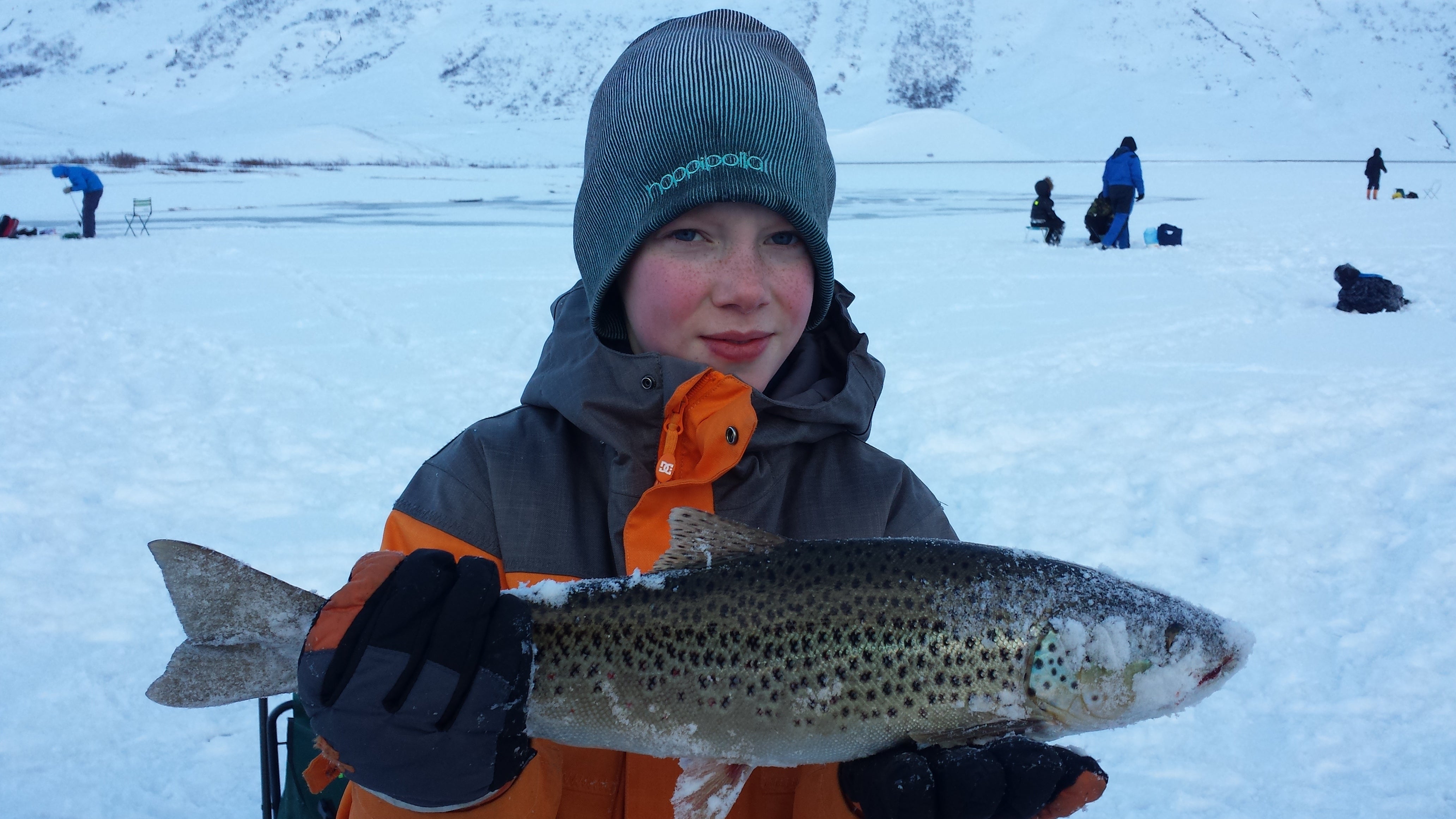 An ice fishing tour participant posing with a huge trout.