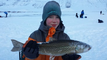 Een deelnemer aan een ijsvistocht poseert met een enorme forel.