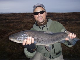 A man smiles as he holds up his catch on a tour in Iceland.