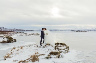 A couple enjoy an enchanting wedding ceremony at Thingvellir National Park surrounded by snow-covered landscapes.