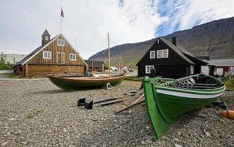 Dos barcos de madera en la costa de Isafjordur con un edificio detrás.