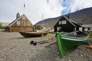 Due barche di legno sulla costa di Isafjordur con un edificio alle spalle