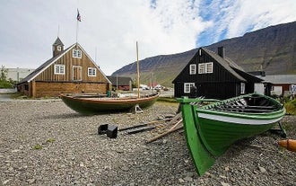 Due barche di legno sulla costa di Isafjordur con un edificio alle spalle