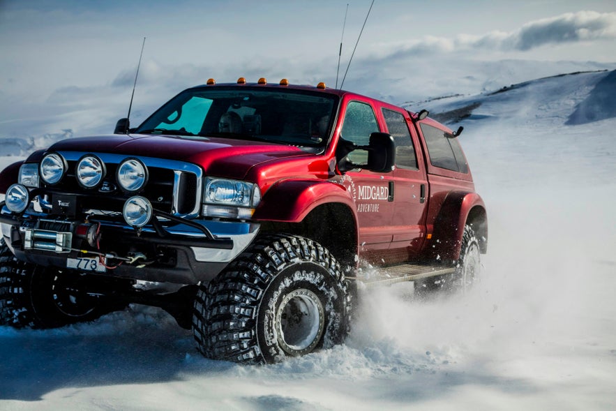 Icelander driving a red super jeep across snowy terrain in Iceland’s Highlands during a winter adventure.