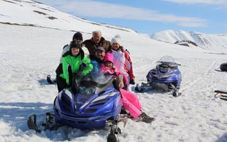 Eine Gruppe von Menschen posiert für ein Foto auf einem Schneemobil während einer Tour in Island.