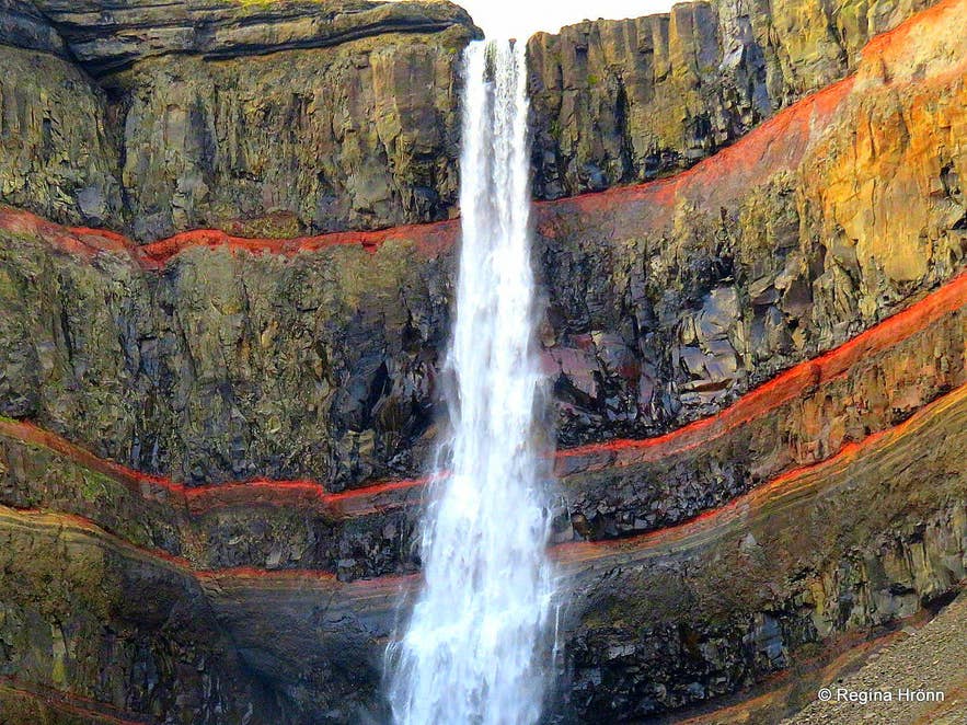 Er zit een prachtige rode kleur in de rotsen achter de Hengifoss waterval in Oost-IJsland