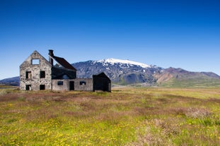 The glacier-capped Snaefellsjokull volcano looks majestic with an abandoned building in the foreground.