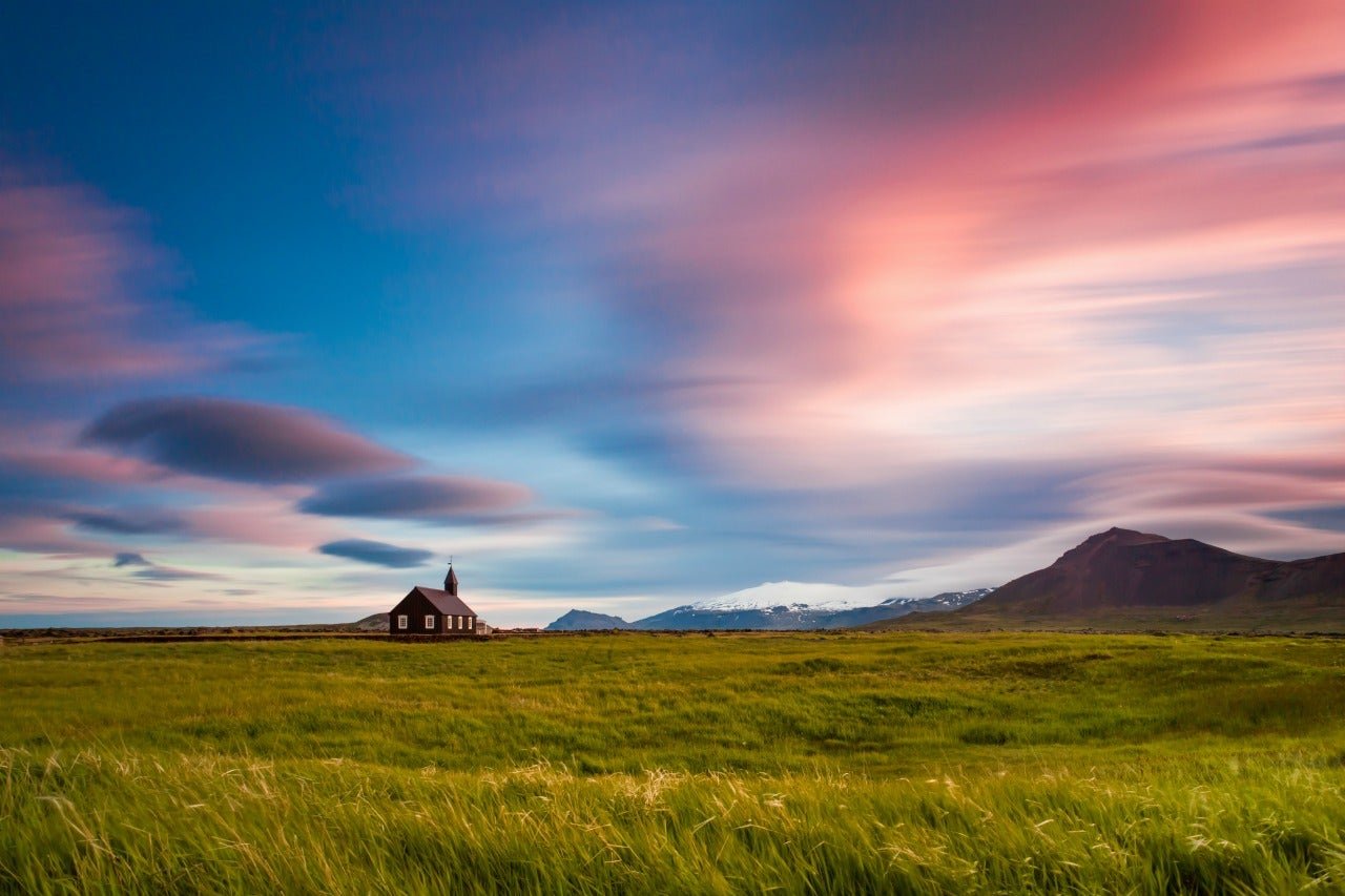 Grasses and mountains surround the lonely black church of Budir in Snaefellsnes.