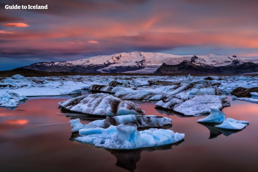 Icebergs floating in Jokulsarlon Glacier Lagoon in Iceland at sunset, with colorful autumn sky reflected on calm water