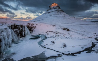Det pyramideformede bjerg Kirkjufell og dets tilstødende vandfald Kirkjufellsfoss bliver klædt i is og sne i vinterens iskolde måneder.
