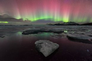 Zorza polarna świeci nad laguną lodowcową Jokulsarlon.