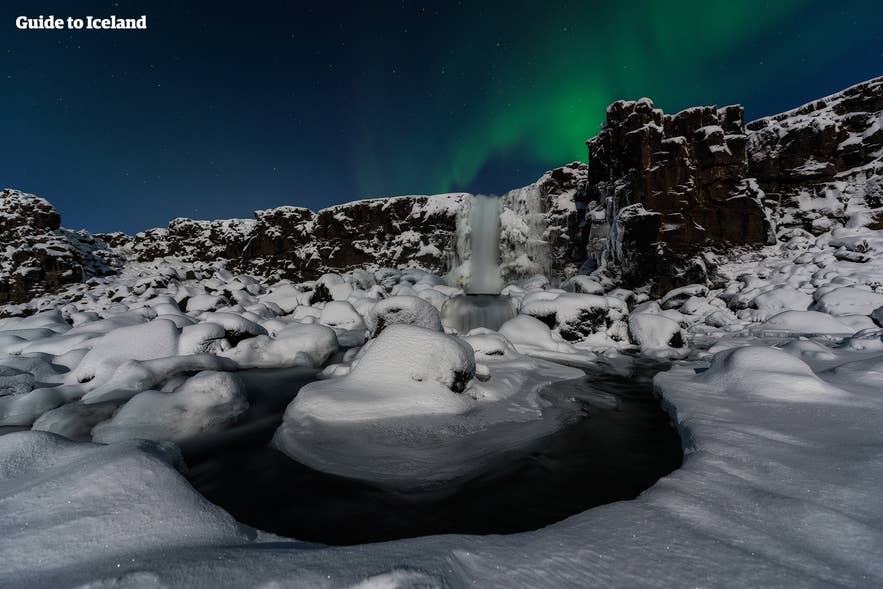 La cascata Oxararfoss coperta di neve sotto l’aurora, uno spettacolo mozzafiato in Islanda a febbraio
