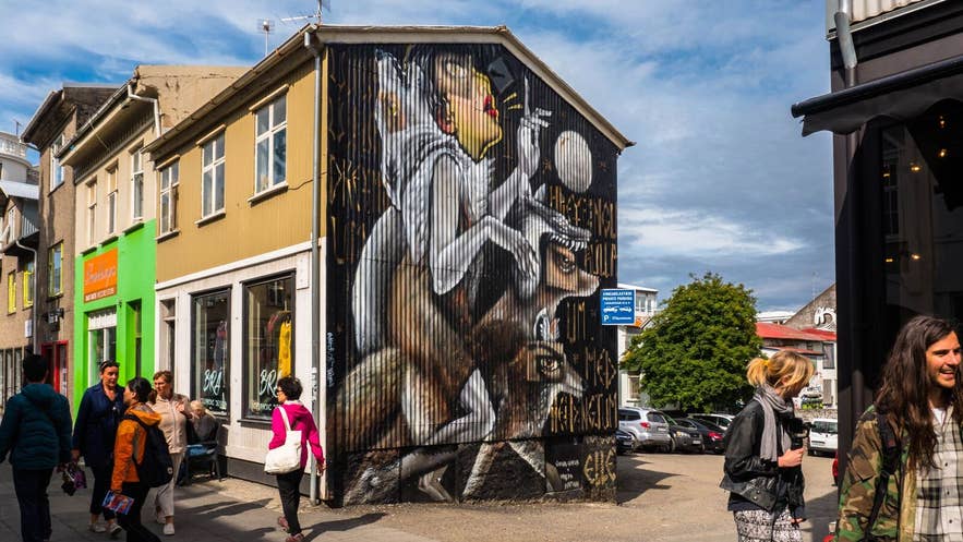 Murale colorato su Laugavegur a Reykjavik, Islanda, con passanti davanti a una facciata dipinta sotto un cielo estivo parzialmente nuvoloso.