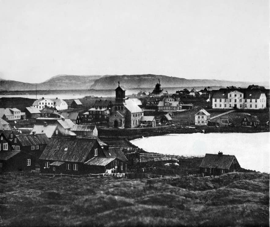 Historische Aufnahme von Reykjavík um 1840 mit dem Tjörnin-See, dem Dom von Reykjavík, dem Menntaskolinn i Reykjavik sowie weiteren frühen Stadtgebäuden.