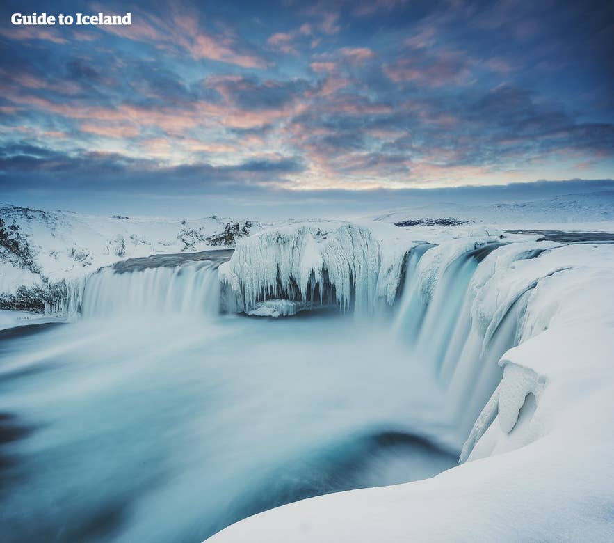 Frozen Godafoss surrounded by snow and icy cliffs, a breathtaking highlight of February in Iceland