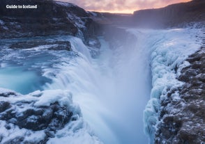 Chute d'eau de Gullfoss en hiver libérant des embruns glaciaux qui gèlent sur les roches et la mousse autour, créant une image dramatique de l'hiver.