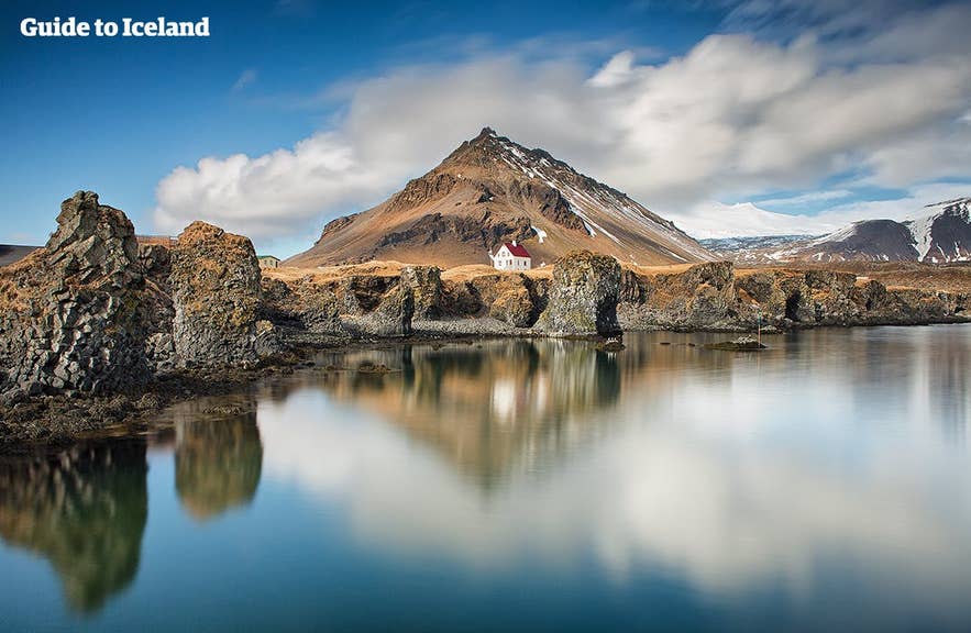 Costa de Arnarstapi y monte Stapafell en la península de Snaefellsnes en Islandia en julio con reflejos tranquilos y nubes dispersas.