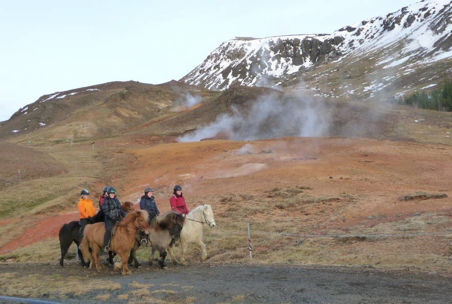 Riders passing steaming hot springs in South Iceland