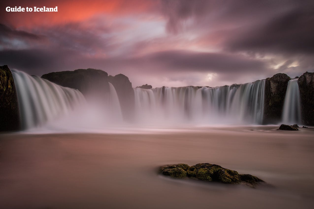 Godafoss vattenfall målat rosa av kvällssolen på Island.
