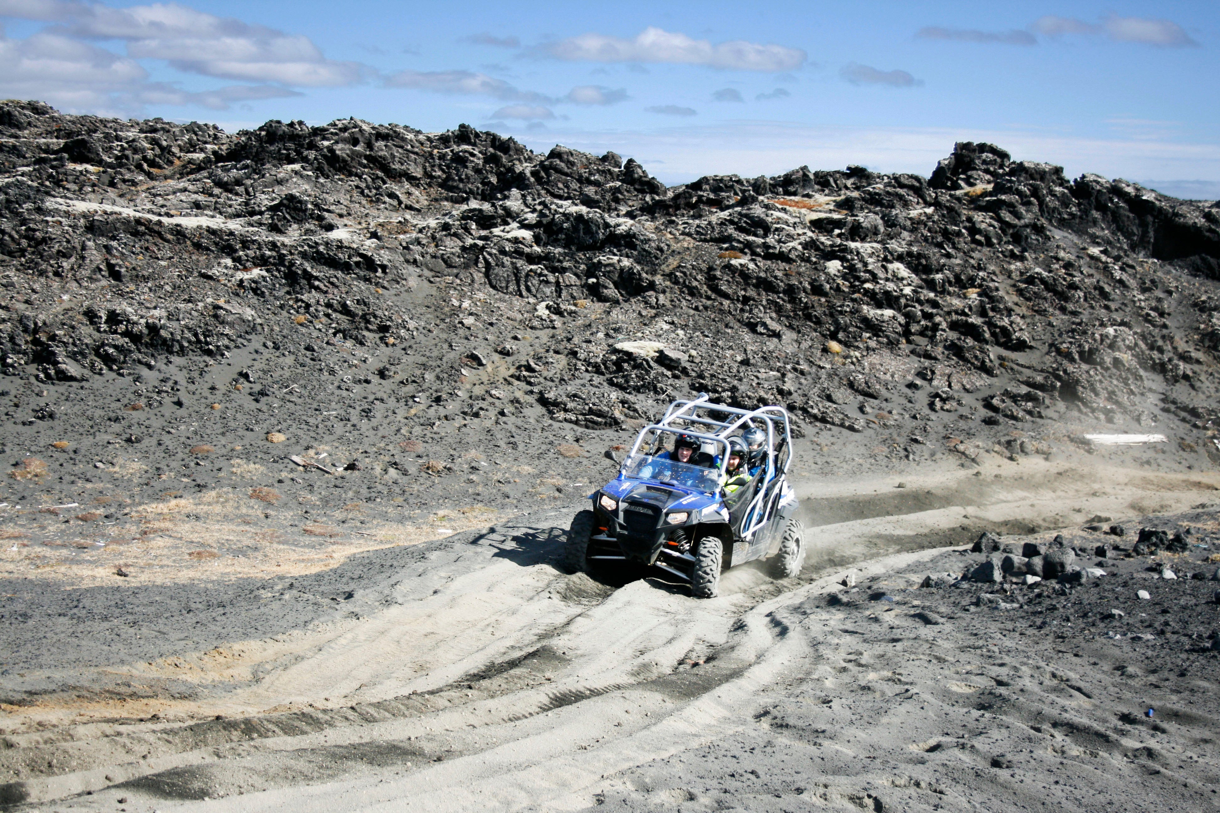 A quad ATV vehicle drives over a black sand beach in Iceland.