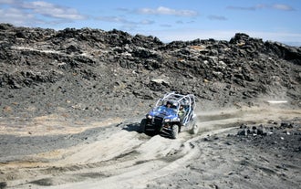 A quad ATV vehicle drives over a black sand beach in Iceland.