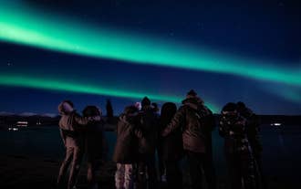 A group gathers under the aurora borealis during a northern lights tour in Iceland.