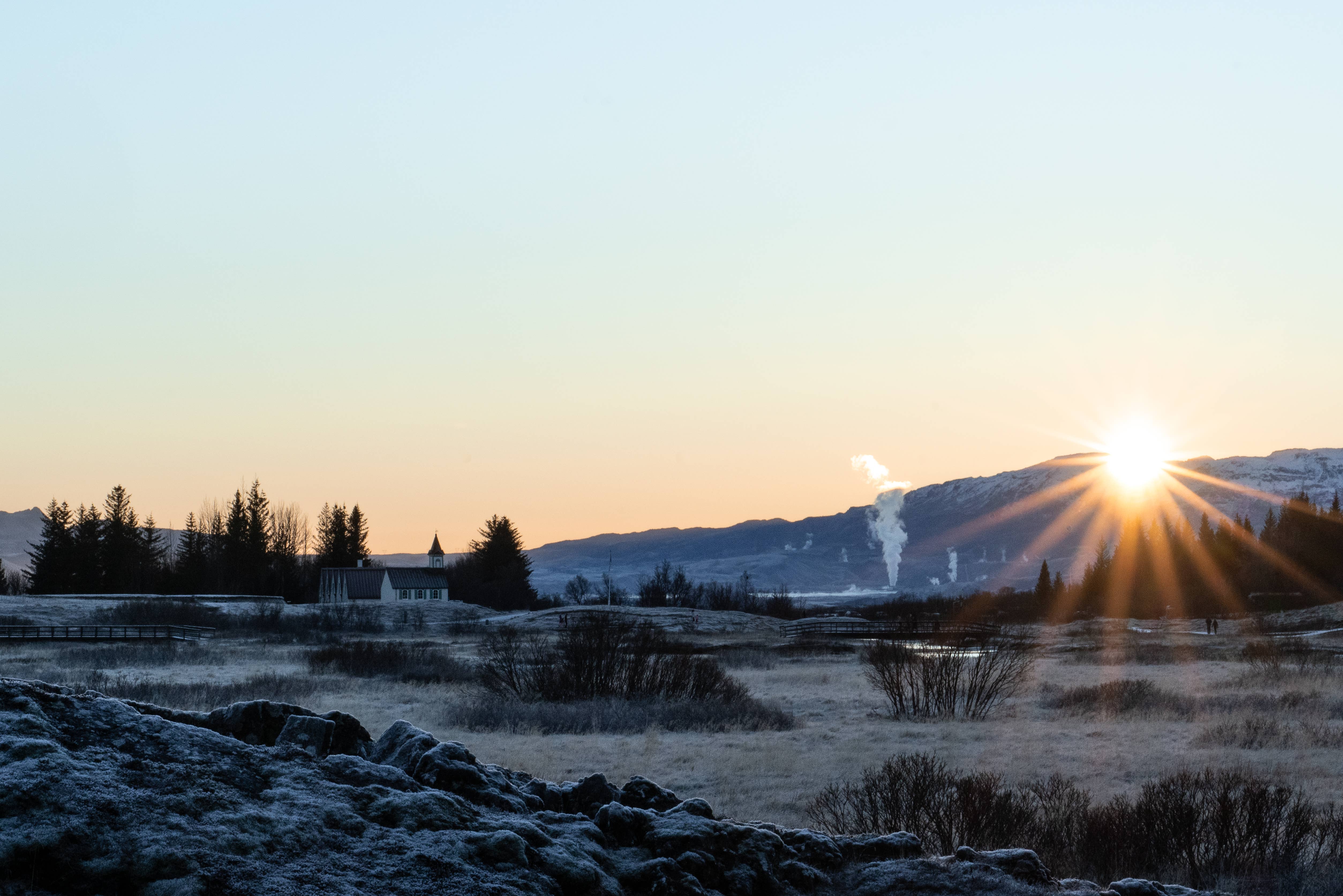 The sun sets behind a snowy mountain in Thingvellir National Park.
