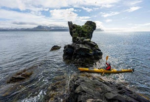 A kayaker passing through a rock formation in the Westfjords region.