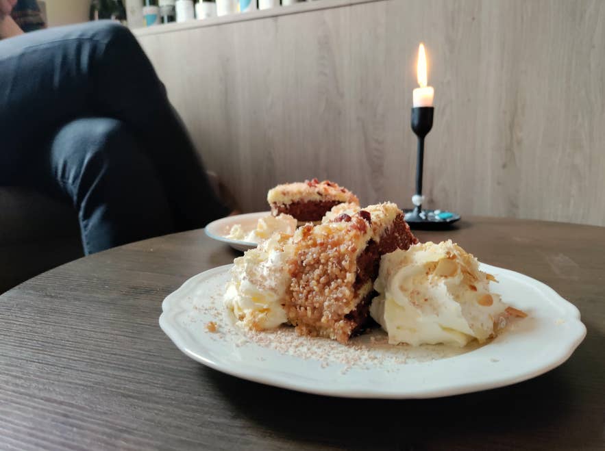 Litli Barinnの居心地の良いコーナーで、キャロットケーキとホイップクリーム、温かなキャンドルの灯り。 Litli Barinnの居心地の良いコーナーで、キャロットケーキとホイップクリーム、温かなキャンドルの灯り。