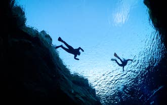 Vista subacquea di persone che praticano snorkeling che galleggiano vicino alle pareti rocciose della fessura di Silfra in Islanda.
