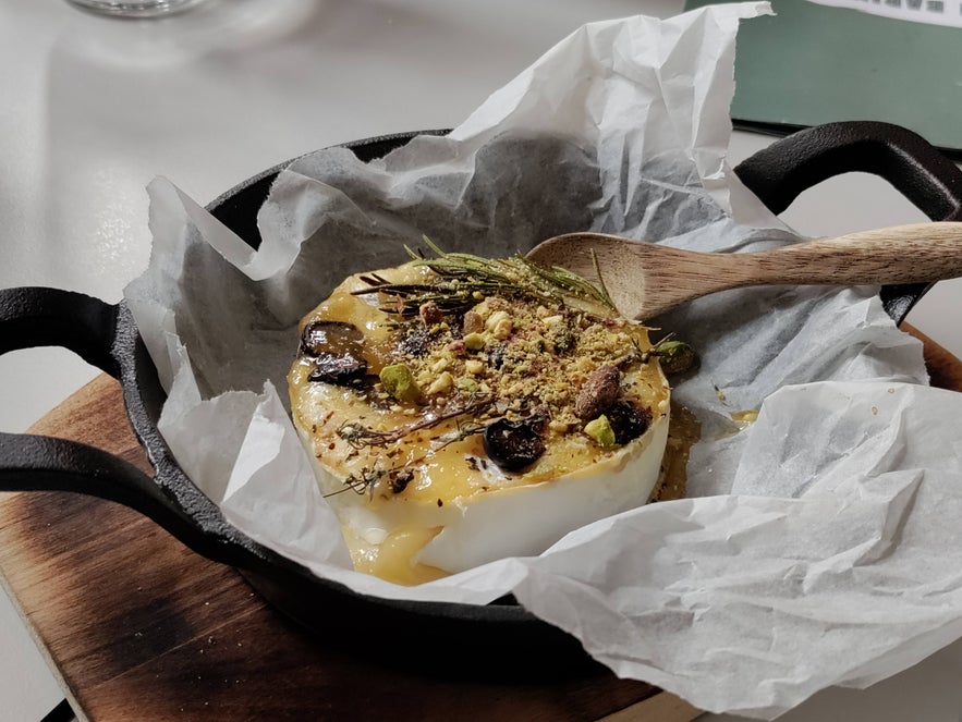 Baked brie topped with nuts, herbs, and honey, served in a cast iron pan at Litli Barinn. Baked brie topped with nuts, herbs, and honey, served in a cast iron pan at Litli Barinn.