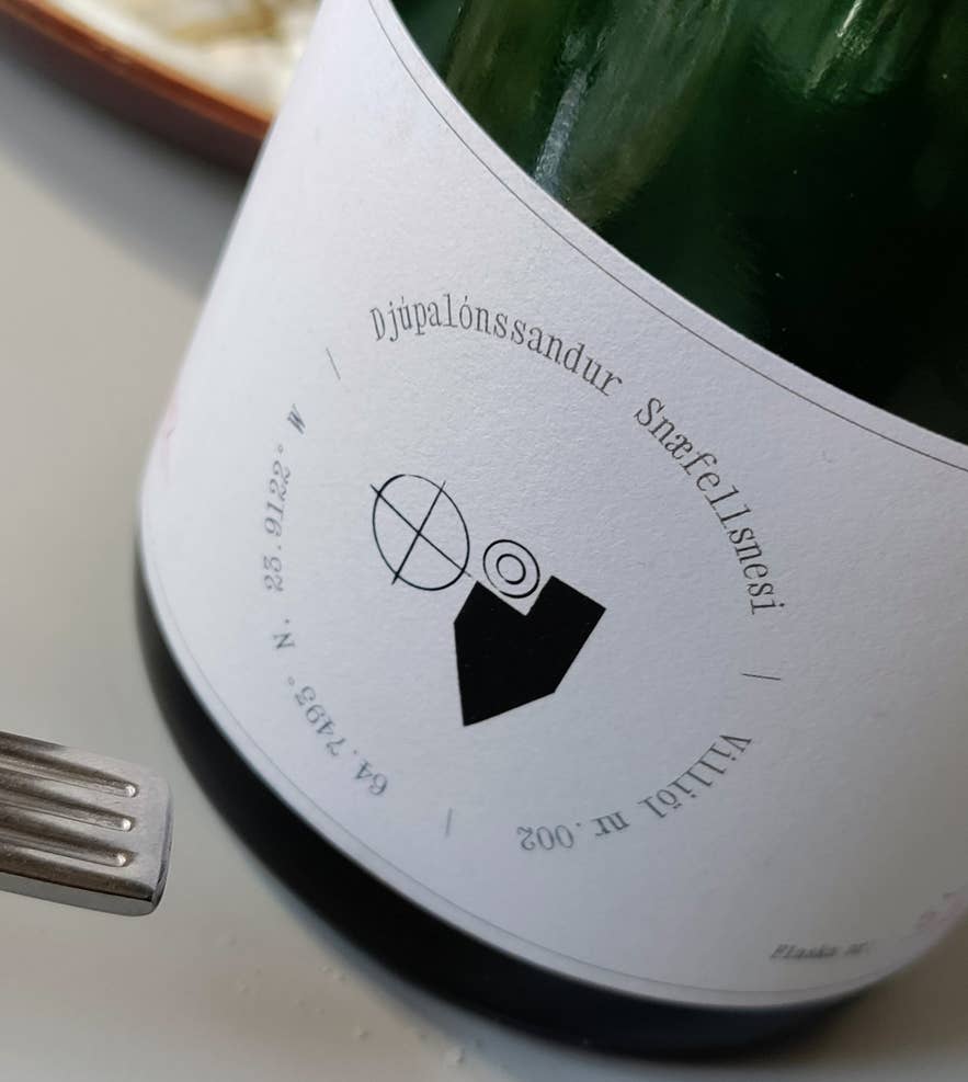 Close-up van een wijnfles met het etiket Djupalonssandur Snaefellsnesi, geserveerd bij Litli Barinn. Close-up van een wijnfles met het etiket Djupalonssandur Snaefellsnesi, geserveerd bij Litli Barinn.