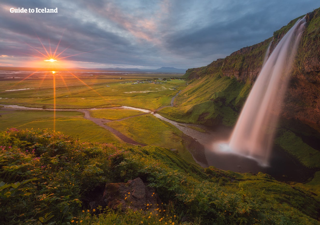 Sonnenuntergang über dem Seljalandsfoss-Wasserfall an der Südküste, der sich über eine ausgehöhlte Felswand stürzt