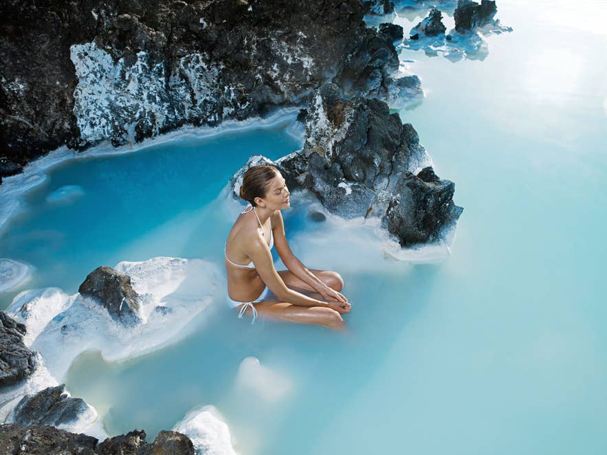 Woman relaxing in Blue Lagoon Geothermal Spa on Reykjanes Peninsula, showing nudity in Iceland and designated bathing areas.