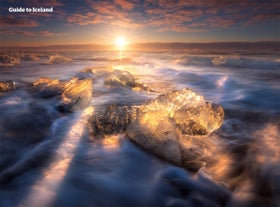 Eisberge glitzern unter der tiefstehenden Sonne am Diamond Beach in der Nähe der Gletscherlagune Jökulsarlon.