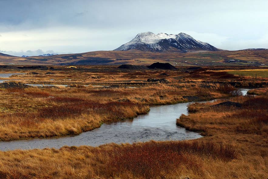 Snow-capped Thrihyrningur Mountain above autumn moorland and a winding river near Hvolsvollur