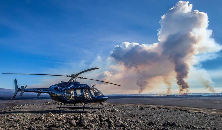 A helicopter overlooking the flaming crevasses of Holahraun Lava Fields.