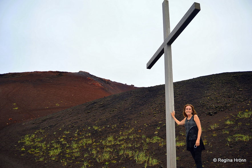 Regína by A memorial cross at the roots of Eldfell volcano