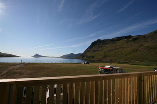 The view of a mountain and fjord from a patio at the Urdartindur Guesthouse.